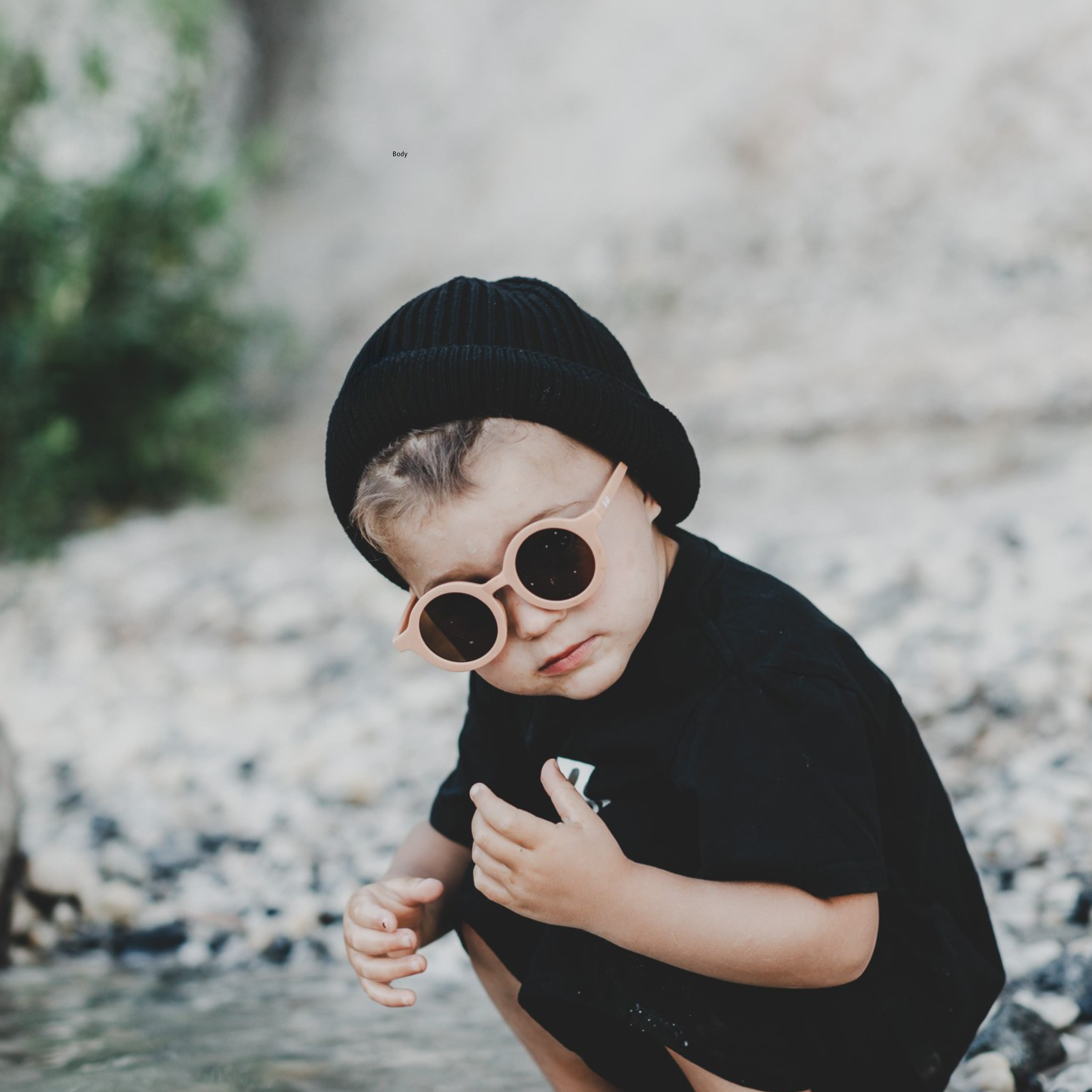 Kid wearing a black organic cotton beanie, unisex design, gazing at the water, enjoying a peaceful moment with sustainable fashion.