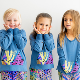Three children posing in a two-piece kids loungewear set with a cactus print and harem pants.