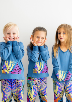 Three children posing in a two-piece kids loungewear set with a cactus print and harem pants.