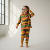 Child wearing a colorful outfit standing in a bright room with large windows.