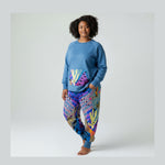 Woman wearing a blue sweatshirt and colorful  pants on a white background