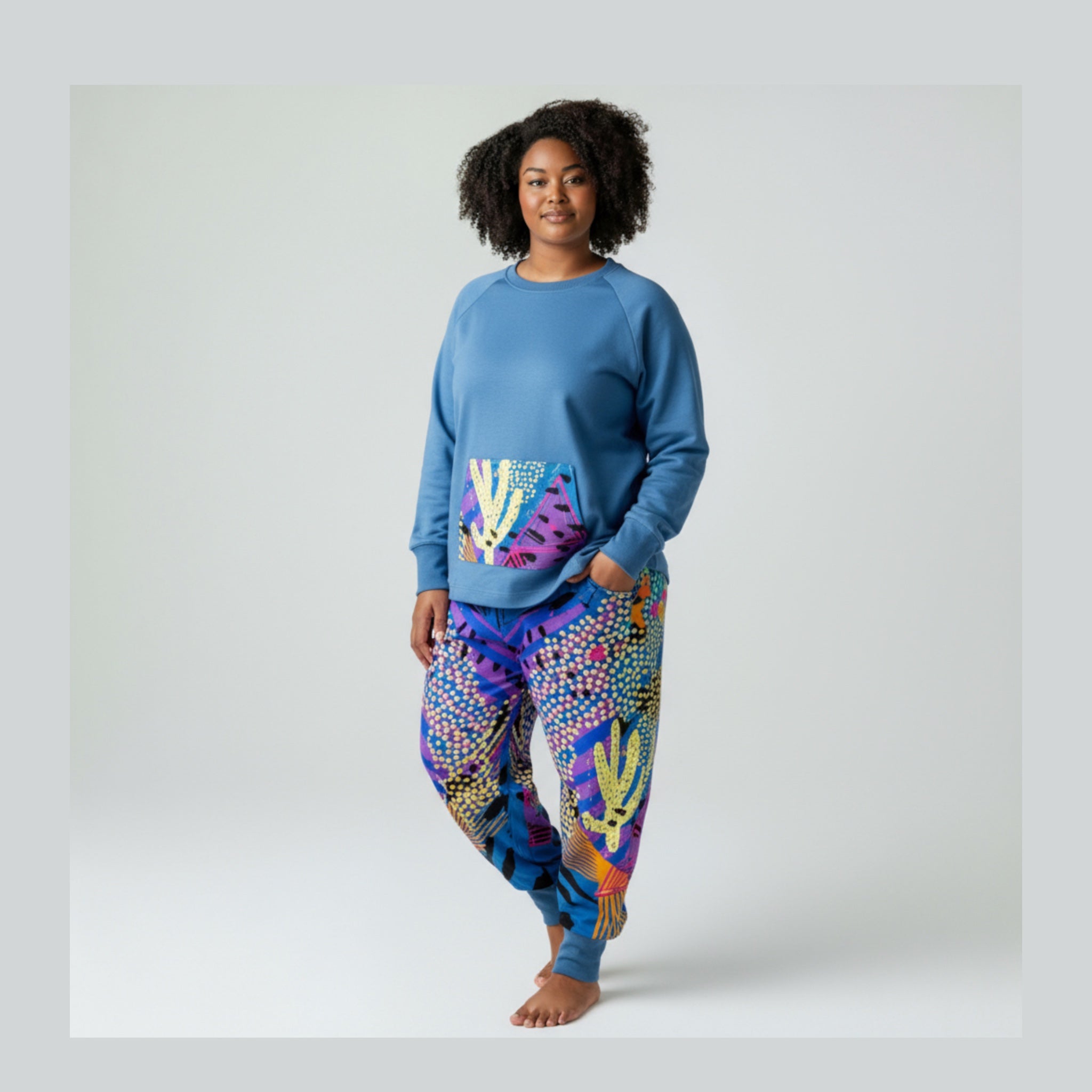 Woman wearing a blue sweatshirt and colorful  pants on a white background